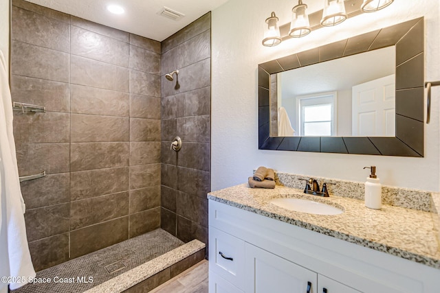 bathroom featuring visible vents, vanity, and a tile shower