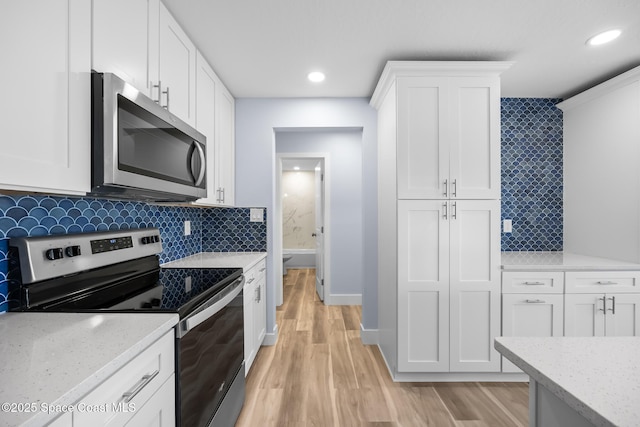 913 Algardi St SE, Palm Bay, FL 32909 - kitchen with appliances with stainless steel finishes, white cabinets, light wood-style floors, light stone countertops, and recessed lighting