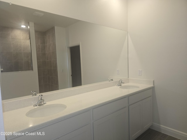 full bath with a sink, baseboards, and double vanity