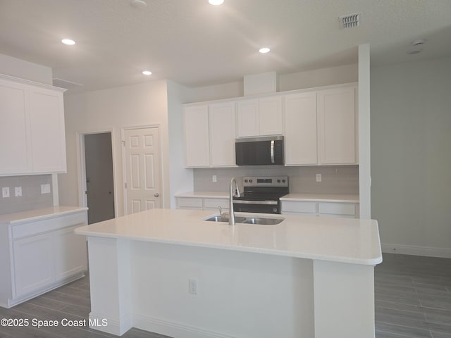 kitchen featuring visible vents, a sink, decorative backsplash, stainless steel appliances, and white cabinets