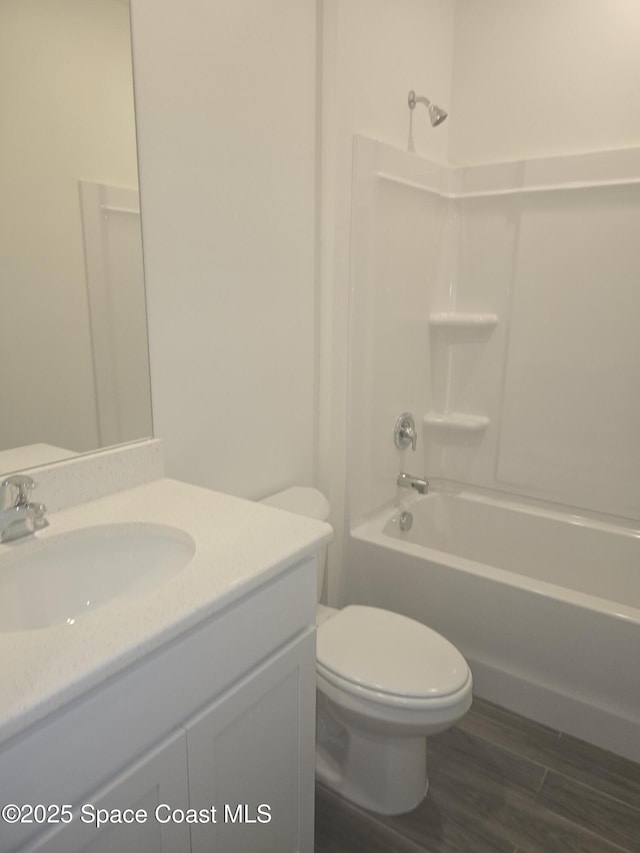 bathroom featuring vanity, toilet, wood finished floors, and shower / washtub combination