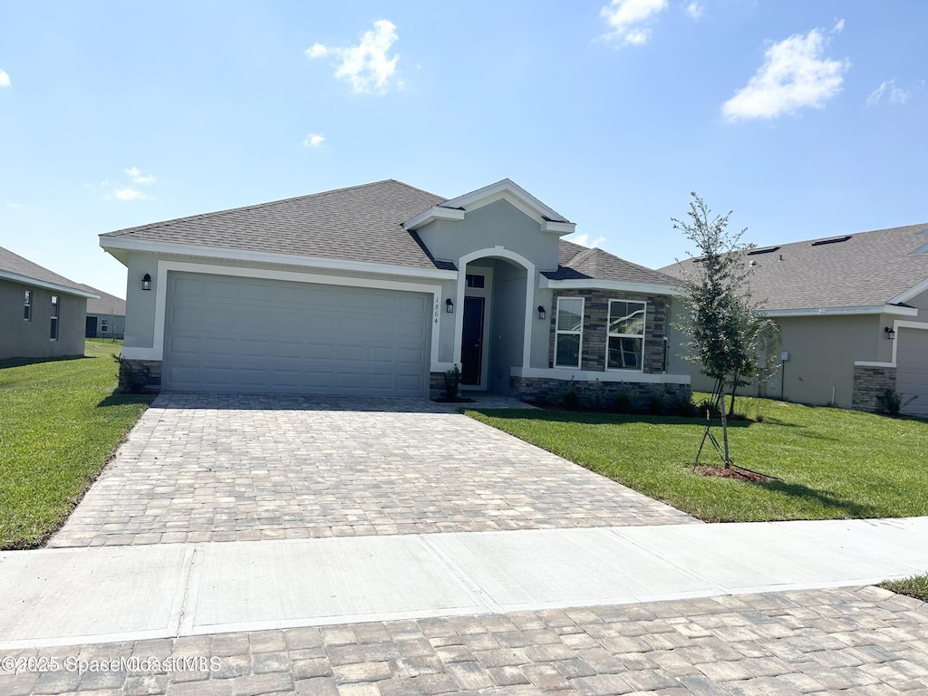 single story home featuring stucco siding, a front lawn, decorative driveway, an attached garage, and a shingled roof