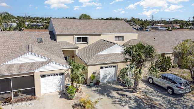 traditional home featuring stucco siding, concrete driveway, a garage, and a shingled roof