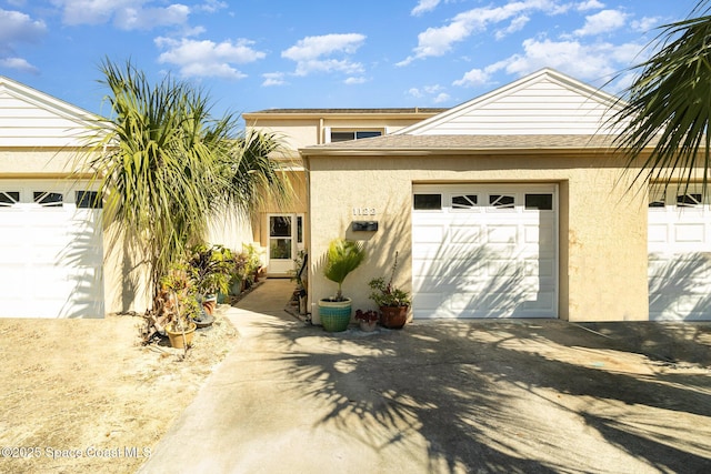 view of front of property featuring stucco siding, driveway, and roof with shingles