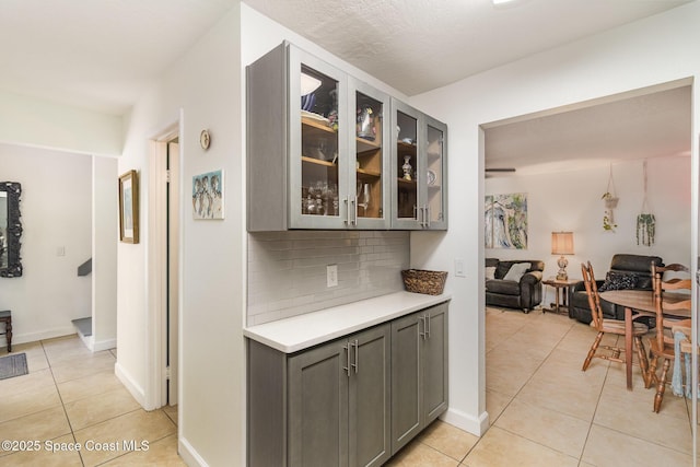 interior space featuring light countertops, light tile patterned floors, glass insert cabinets, and gray cabinetry