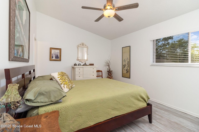 bedroom featuring baseboards, wood finished floors, a ceiling fan, and vaulted ceiling