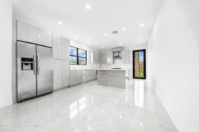 kitchen with visible vents, marble finish floor, modern cabinets, stainless steel fridge with ice dispenser, and wall chimney range hood