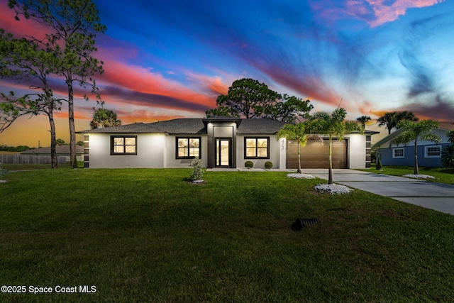 view of front of property featuring stucco siding, an attached garage, a yard, and driveway