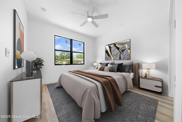 bedroom featuring ceiling fan, light wood-type flooring, and baseboards