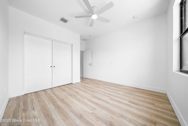 unfurnished bedroom featuring visible vents, ceiling fan, baseboards, light wood-style floors, and a closet