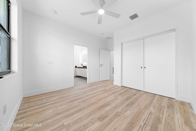 unfurnished bedroom featuring wood finished floors, baseboards, visible vents, ensuite bath, and a closet