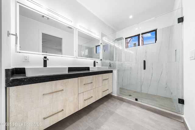 bathroom with double vanity, visible vents, a marble finish shower, and a sink