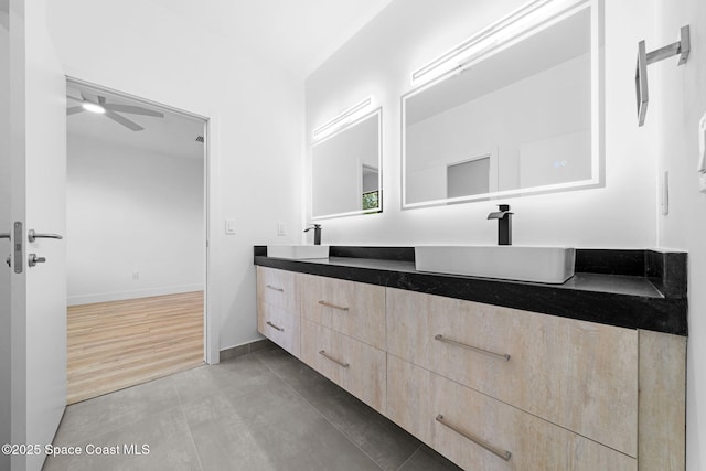 full bath featuring baseboards, double vanity, tile patterned floors, a ceiling fan, and a sink