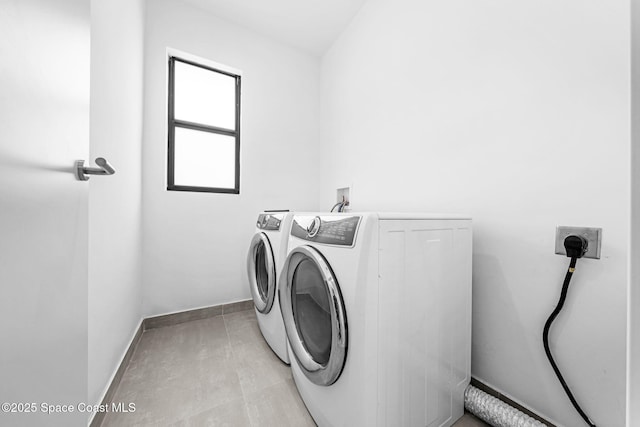 clothes washing area featuring baseboards, separate washer and dryer, and laundry area