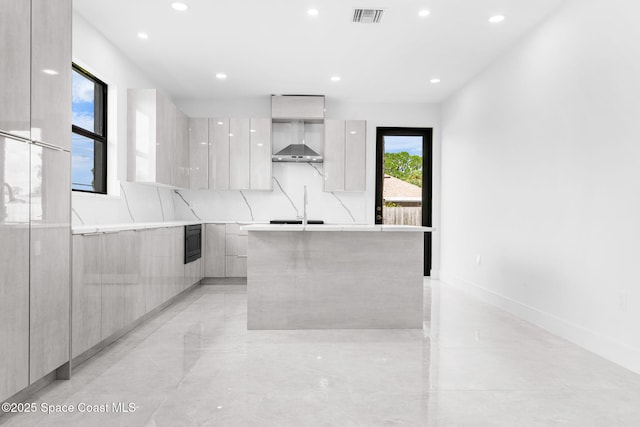 kitchen with visible vents, a kitchen island, decorative backsplash, modern cabinets, and wall chimney exhaust hood