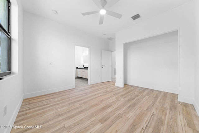 unfurnished bedroom featuring visible vents, light wood-style flooring, connected bathroom, and baseboards