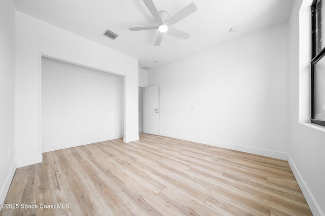 unfurnished bedroom featuring wood finished floors, visible vents, baseboards, ceiling fan, and a closet