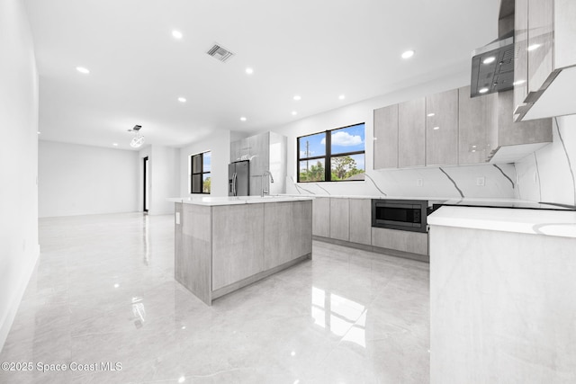 kitchen featuring visible vents, modern cabinets, a kitchen island with sink, stainless steel fridge with ice dispenser, and built in microwave