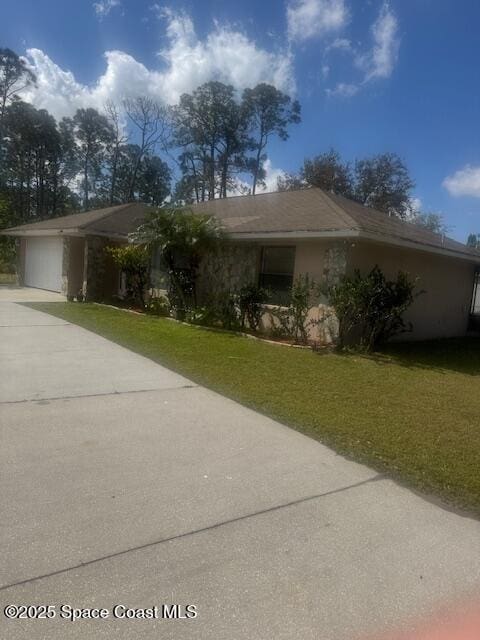 view of front of property with stucco siding, driveway, an attached garage, and a front yard