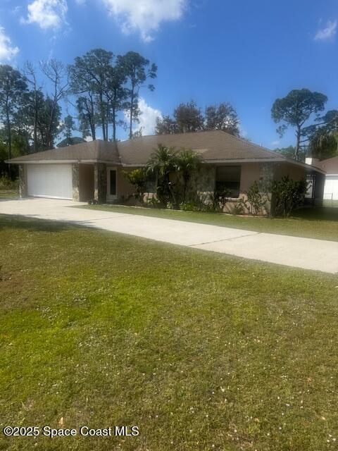 single story home featuring stucco siding, a front yard, an attached garage, and driveway