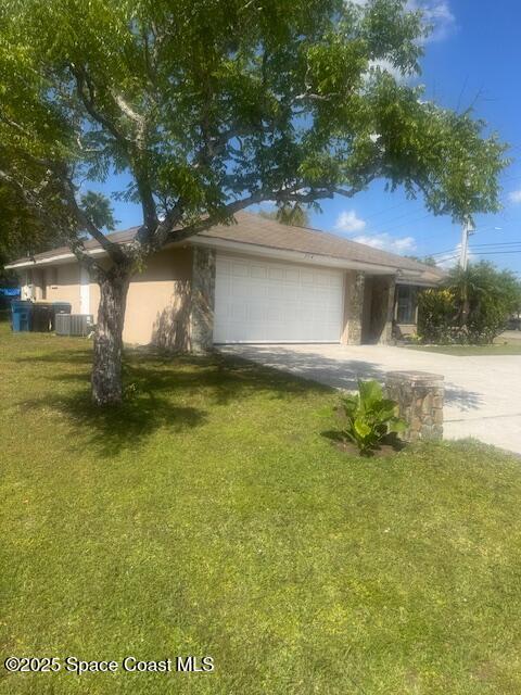 view of front of house with driveway, stucco siding, a front lawn, a garage, and central air condition unit