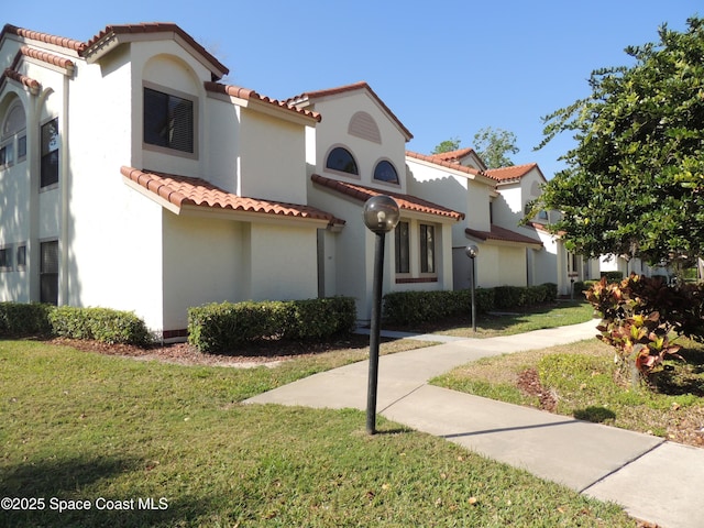 mediterranean / spanish-style home with stucco siding, a front lawn, and a tiled roof