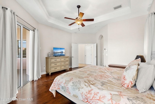 3338 Cappio Dr, Melbourne, FL 32940 - bedroom featuring visible vents, access to exterior, a tray ceiling, arched walkways, and wood finished floors