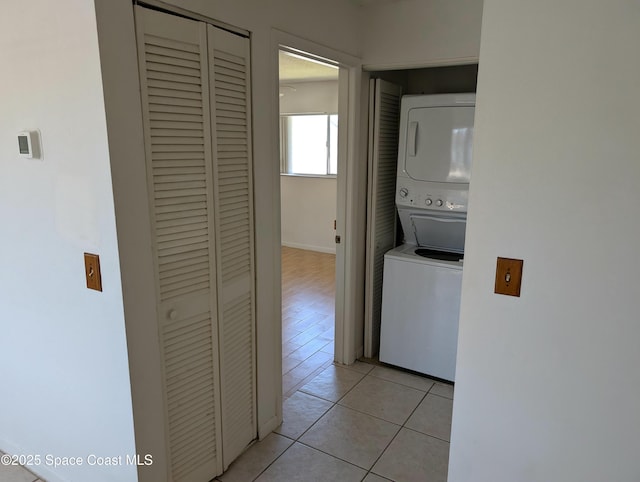 clothes washing area with light tile patterned floors, stacked washer / drying machine, and laundry area