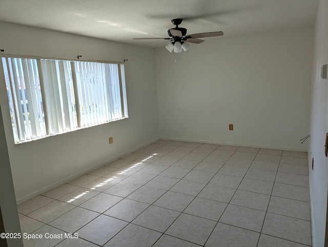 unfurnished room featuring light tile patterned flooring, a ceiling fan, and baseboards