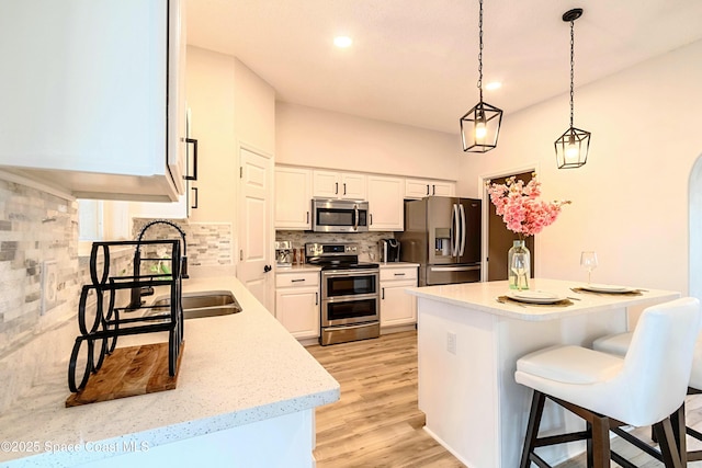 4026 Four Lakes Dr, Melbourne, FL 32940 - kitchen featuring a kitchen island, a kitchen breakfast bar, appliances with stainless steel finishes, white cabinets, and decorative backsplash