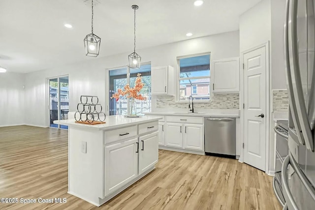 4026 Four Lakes Dr, Melbourne, FL 32940 - kitchen with white cabinets, light wood-style flooring, appliances with stainless steel finishes, a sink, and backsplash