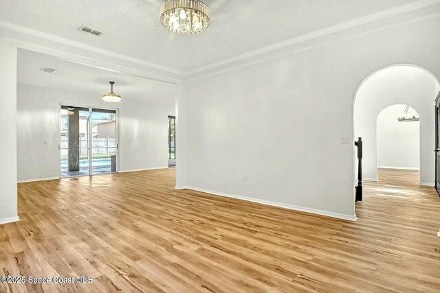 4026 Four Lakes Dr, Melbourne, FL 32940 - empty room featuring a textured ceiling, light wood-type flooring, baseboards, ornamental molding, and an inviting chandelier