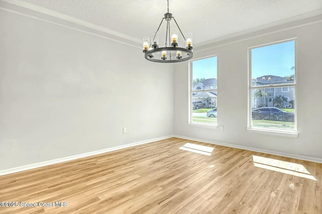4026 Four Lakes Dr, Melbourne, FL 32940 - empty room featuring a textured ceiling, crown molding, baseboards, light wood-type flooring, and a notable chandelier