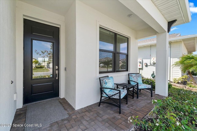 property entrance featuring covered porch and stucco siding