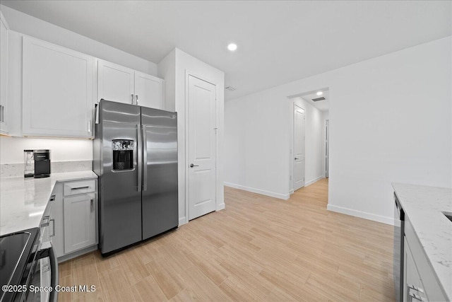 kitchen with light stone countertops, baseboards, stainless steel refrigerator with ice dispenser, range with electric stovetop, and light wood-type flooring