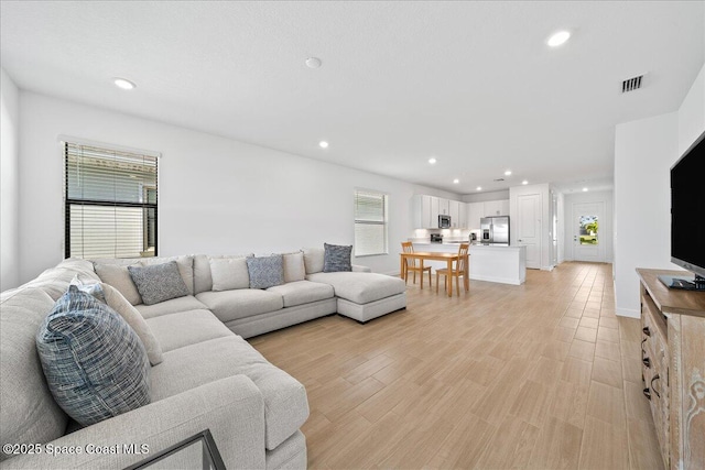 living area featuring recessed lighting, light wood-style floors, visible vents, and baseboards