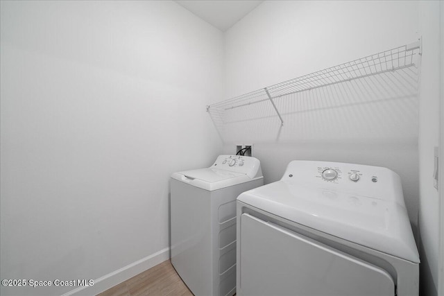 laundry room with laundry area, light wood-style floors, baseboards, and washing machine and clothes dryer