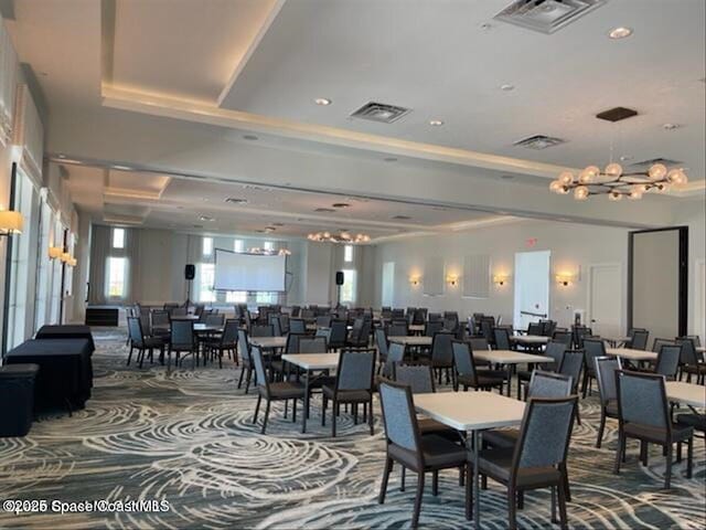 dining area with a tray ceiling, a notable chandelier, and visible vents