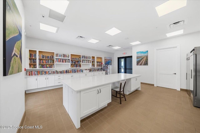 kitchen with a skylight, visible vents, white cabinets, and a center island