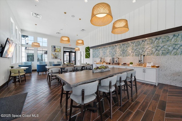 kitchen with visible vents, wood finish floors, wallpapered walls, white cabinets, and decorative light fixtures