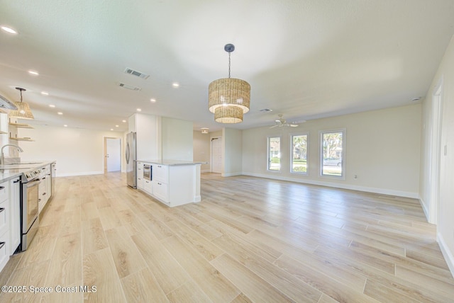 kitchen with visible vents, light wood-style flooring, a sink, stainless steel appliances, and white cabinets