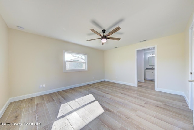 spare room with visible vents, light wood-style flooring, a ceiling fan, and baseboards