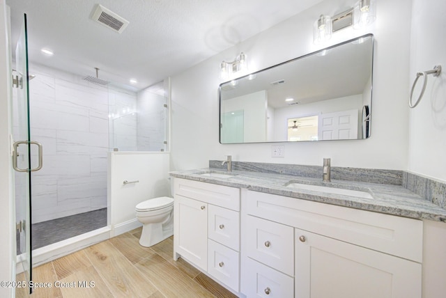 full bath featuring visible vents, a stall shower, toilet, and a sink