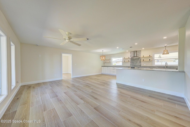 unfurnished living room featuring baseboards, recessed lighting, a sink, ceiling fan, and light wood-type flooring