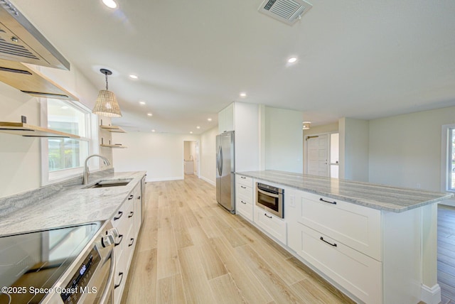 kitchen with light wood-type flooring, a sink, open shelves, stainless steel appliances, and white cabinets