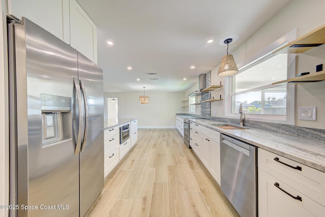 kitchen featuring a sink, open shelves, stainless steel appliances, white cabinets, and light stone countertops