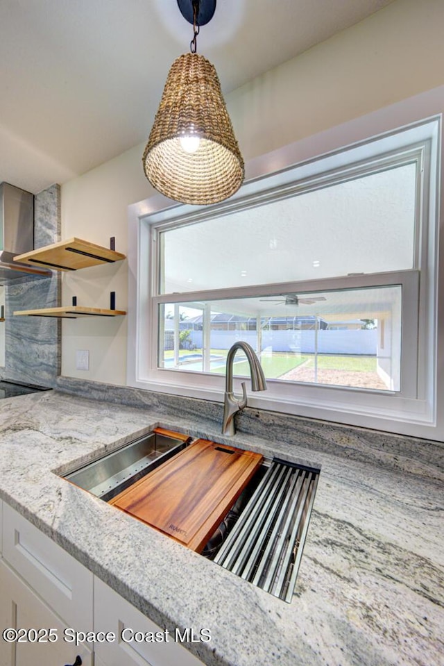 kitchen featuring light stone counters, pendant lighting, white cabinetry, and open shelves