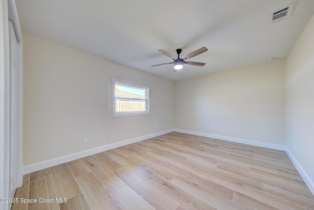 spare room featuring visible vents, baseboards, light wood-style flooring, and a ceiling fan