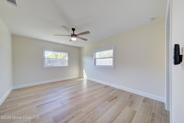 empty room with a wealth of natural light, visible vents, light wood-style flooring, and a ceiling fan