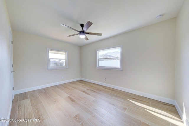 spare room featuring a ceiling fan, light wood-style floors, and baseboards